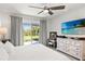 Bright bedroom with a ceiling fan, large dresser, and sliding doors leading to the outside at 12959 Seasong Ter, Bradenton, FL 34211
