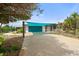 Charming home exterior featuring a vibrant blue garage door and sun shade with a well manicured yard at 1410 San Jose Dr, Englewood, FL 34223
