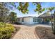 Beautiful home exterior with a tiki hut, brick pavers, and lush landscaping in a serene setting at 1410 San Jose Dr, Englewood, FL 34223