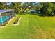 Backyard view featuring a sparkling pool, lush green lawn, and serene lake at 1525 Fleetwood Dr, Sarasota, FL 34232