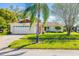 Alluring home front, featuring a lush green lawn, a decorative palm, and a striking red entrance door at 1525 Fleetwood Dr, Sarasota, FL 34232