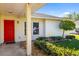 Inviting entryway featuring a bright red door, decorative lighting, and neatly landscaped shrubs and stone at 1525 Fleetwood Dr, Sarasota, FL 34232