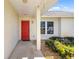 Charming covered entry with a striking red front door, complemented by manicured shrubs and stone ground cover at 1525 Fleetwood Dr, Sarasota, FL 34232