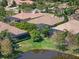 Aerial view of homes with screened lanais surrounding a pond, complemented by lush greenery and mature trees at 15508 Leven Links Pl, Lakewood Ranch, FL 34202