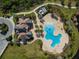Aerial view of a clubhouse, featuring a unique pool design, meticulous landscaping and surrounding greenery at 15508 Leven Links Pl, Lakewood Ranch, FL 34202