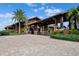 Exterior view of a clubhouse entrance with a porte cochere, lush landscaping, and a brick-paved driveway at 15508 Leven Links Pl, Lakewood Ranch, FL 34202