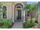Elegant front entrance with an arched doorway and decorative pillars surrounded by beautiful landscaping at 15508 Leven Links Pl, Lakewood Ranch, FL 34202