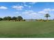 Scenic golf course with a lake view, manicured greens, and lush landscaping under a blue sky with clouds at 15508 Leven Links Pl, Lakewood Ranch, FL 34202