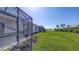 Home backyard with lush green lawn and screened in lanai overlooking scenic lake view at 18137 Franklin Park Ct, Venice, FL 34293