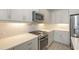 Gourmet kitchen features stainless appliances, white cabinetry, and quartz counters with tile backsplash at 18137 Franklin Park Ct, Venice, FL 34293