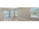 An empty room with neutral colored walls, many windows, lots of sunlight and sliding glass doors to a patio at 18137 Franklin Park Ct, Venice, FL 34293