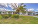 Inviting single-story home featuring lush greenery and a large palm tree in the front yard at 22201 Olean Blvd, Port Charlotte, FL 33952