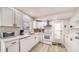 Well-lit kitchen with stainless steel appliances, white cabinets, gray floors, and a door leading to the exterior at 22201 Olean Blvd, Port Charlotte, FL 33952