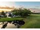 A stunning home overlooks a serene pond, reflecting the picturesque landscaping and golden hour sky at 236 Saint James Park, Osprey, FL 34229