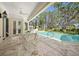 A covered patio with a table and chairs overlooks a beautiful swimming pool and landscaped backyard at 236 Saint James Park, Osprey, FL 34229