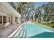 An in-ground pool with stone trim is surrounded by lush greenery and a spacious backyard at 236 Saint James Park, Osprey, FL 34229