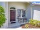 Inviting covered front porch featuring stylish seating and elegant landscaping near a striking front door at 2871 Royal Palm Dr, North Port, FL 34288