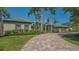 Stunning home exterior with a brick driveway, lush landscaping, and stately palm trees at 316 W Royal Flamingo Dr, Sarasota, FL 34236