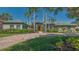 Stunning single-story home exterior showcasing well-manicured lawn, tropical trees, and a brick driveway at 316 W Royal Flamingo Dr, Sarasota, FL 34236