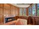 Cozy living area with a fireplace, wood paneling, and large window overlooking lush greenery creates a serene retreat at 316 W Royal Flamingo Dr, Sarasota, FL 34236
