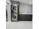 Modern laundry area featuring a stacked washer and dryer unit, storage cabinets, and countertop space at 3234 Restful Ln, Sarasota, FL 34231