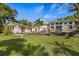 Exterior view of the home displaying its well-maintained lawn, trees, and large backyard wooden deck at 325 12Th W Ave, Palmetto, FL 34221