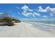 Expansive beach scene highlighting pristine white sand, gentle waves, and clear blue skies dotted with fluffy clouds at 4104 128Th W St # 704, Cortez, FL 34215