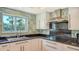 Modern kitchen featuring stone backsplash, black countertops and stainless steel range hood and sink with natural light at 4104 128Th W St # 704, Cortez, FL 34215
