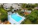 Aerial view of a large in-ground pool surrounded by lush landscaping, a hot tub, and a pool house at 4104 128Th W St # 704, Cortez, FL 34215