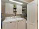Efficient laundry room with white cabinets, washer, dryer and brick accent wall at 4110 Central Sarasota Pkwy # 123, Sarasota, FL 34238