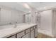 Bright bathroom featuring double sinks, walk-in shower with a clear shower door and white cabinetry at 4231 Autumn Fog Ct, Palmetto, FL 34221