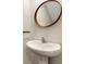 Stylish powder room with a round wooden mirror and a sleek pedestal sink at 4231 Autumn Fog Ct, Palmetto, FL 34221