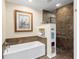 Bathroom featuring tub with tiled accent wall and a glass shower with built-in shelving for towels at 4701 Pine Harrier Dr, Sarasota, FL 34231