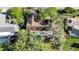 Aerial view from above highlighting the roof and caged pool of a home in a green, wooded community at 4965 Marsh Field Rd, Sarasota, FL 34235