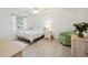 Bright bedroom with a light wood frame bed, white walls and curtains and a cozy green chair at 4965 Marsh Field Rd, Sarasota, FL 34235
