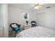 Bright bedroom features white walls, a window with sheer curtains, and is decorated with patterned bedding and blue rattan chairs at 4965 Marsh Field Rd, Sarasota, FL 34235