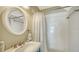 Bathroom featuring a white sink, round mirror, and a shower with white tiled walls and a shower curtain at 5007 2Nd Ave, Holmes Beach, FL 34217