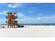 Idyllic beach scene with a lifeguard tower, pristine white sand, and clear blue skies perfect for relaxation at 5007 2Nd Ave, Holmes Beach, FL 34217