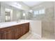 Bright bathroom with a shower, large mirror and dark wood cabinets, offering a luxurious feel at 5011 Kincaid Park Ln, Bradenton, FL 34211