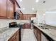 Modern kitchen with granite countertops, stainless steel appliances, dark wood cabinetry, and tile flooring at 5011 Kincaid Park Ln, Bradenton, FL 34211