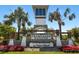 A stately entrance to Promenade Estates on Palmer Ranch, framed by palm trees and colorful flowers at 5744 Woodland Sage Dr, Sarasota, FL 34238