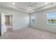 A bright primary bedroom boasts large windows, neutral walls, carpet flooring, and a tray ceiling with a fan at 5744 Woodland Sage Dr, Sarasota, FL 34238