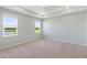 Bright primary bedroom featuring large windows, neutral walls, carpet floors, and a tray ceiling with a fan at 5744 Woodland Sage Dr, Sarasota, FL 34238