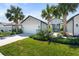 Charming home with a well-manicured lawn, lush landscaping, and inviting curb appeal with palm trees and clean driveway at 5998 Amberly Dr, Bradenton, FL 34208