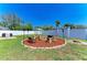 The backyard has a custom firepit with chairs, tropical foliage, and a white fence at 6415 Fetterbush Ln, Lakewood Ranch, FL 34202