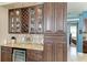 A bar area features wooden cabinets, a wine rack, glass storage, granite counters, and a mini fridge at 6415 Fetterbush Ln, Lakewood Ranch, FL 34202
