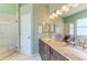 Bathroom features a double sink vanity, granite countertops, framed mirrors, and glass door shower at 6415 Fetterbush Ln, Lakewood Ranch, FL 34202
