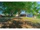 Shaded backyard with mature trees, green lawn, and view of the screened-in lanai at 6639 Electra Ave, North Port, FL 34287