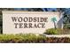 Welcoming community sign reading 'Woodside Terrace' set amidst lush greenery, creating an inviting entrance at 7151 Wood Creek Dr # 205, Sarasota, FL 34231