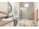 Well-lit bathroom featuring granite countertops, a glass-enclosed shower, and a decorative round mirror at 7211 Prestbury Cir, Lakewood Ranch, FL 34202